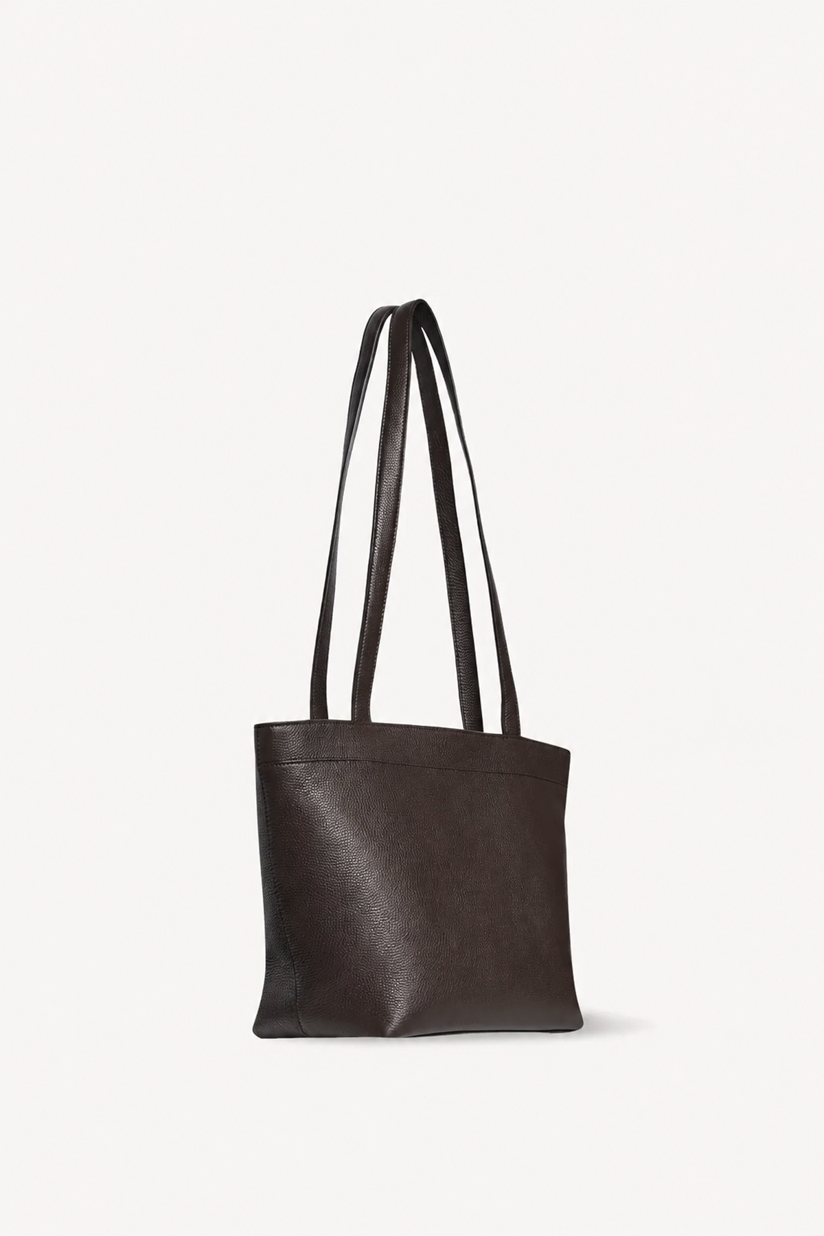 A dark brown leather tote bag with two long shoulder straps, shown from a side profile against a clean, off-white background.
